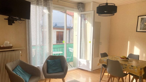 Una habitación acogedora con cama, una mesa de comedor con sillas, televisión y vistas al balcón exterior.