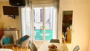 Un comedor con mesa dispuesta para cuatro, un sofá y vista al jardín trasero a través de puertas de cristal.