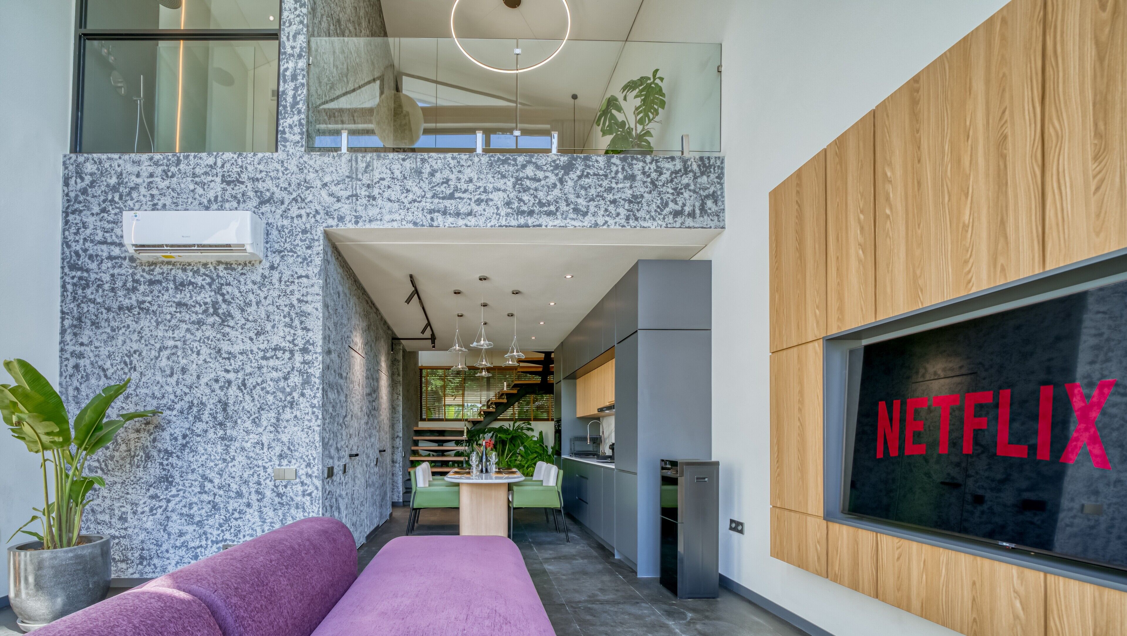 A modern interior with a Netflix sign, a kitchen area, and a seating area with a purple sofa.