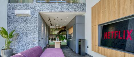 A modern interior with a Netflix sign, a kitchen area, and a seating area with a purple sofa.