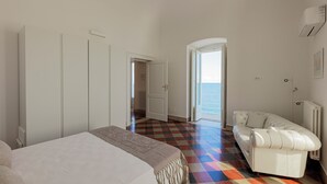 Een slaapkamer met een bed, een witte bank en een kleurrijke geruite vloer.