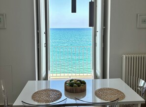 A table with two woven placemats and a bowl of fruit, facing a balcony with a view of the sea. - Ancient Residence On The Sea - Blu - Luxury Apartment With Sea View - Molfetta (Molfetta)