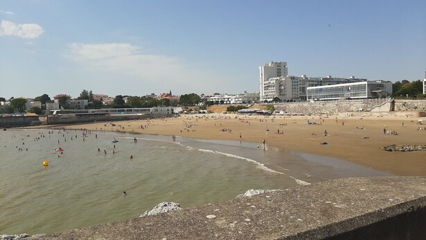 A beach with people swimming and sunbathing, buildings in the background, and a clear sky. - Waterfront 200m from beach (Royan)