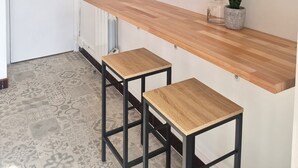 A kitchen with a wooden countertop, two stools, and three framed pictures of famous landmarks. - Waterfront 200m from beach (Royan)