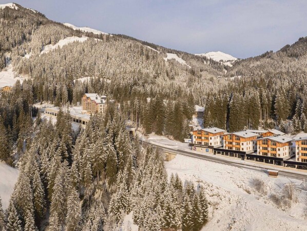 A snow-covered mountain landscape with a ski resort building featuring multiple floors and a ski lift.