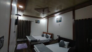 Habitación de hotel con dos camas, un ventilador de techo, un cuadro y una alfombra pequeña.