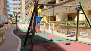 Een parkeergarage met meerdere verdiepingen, met een kinderspeelplaats inclusief schommels en een glijbaan.
