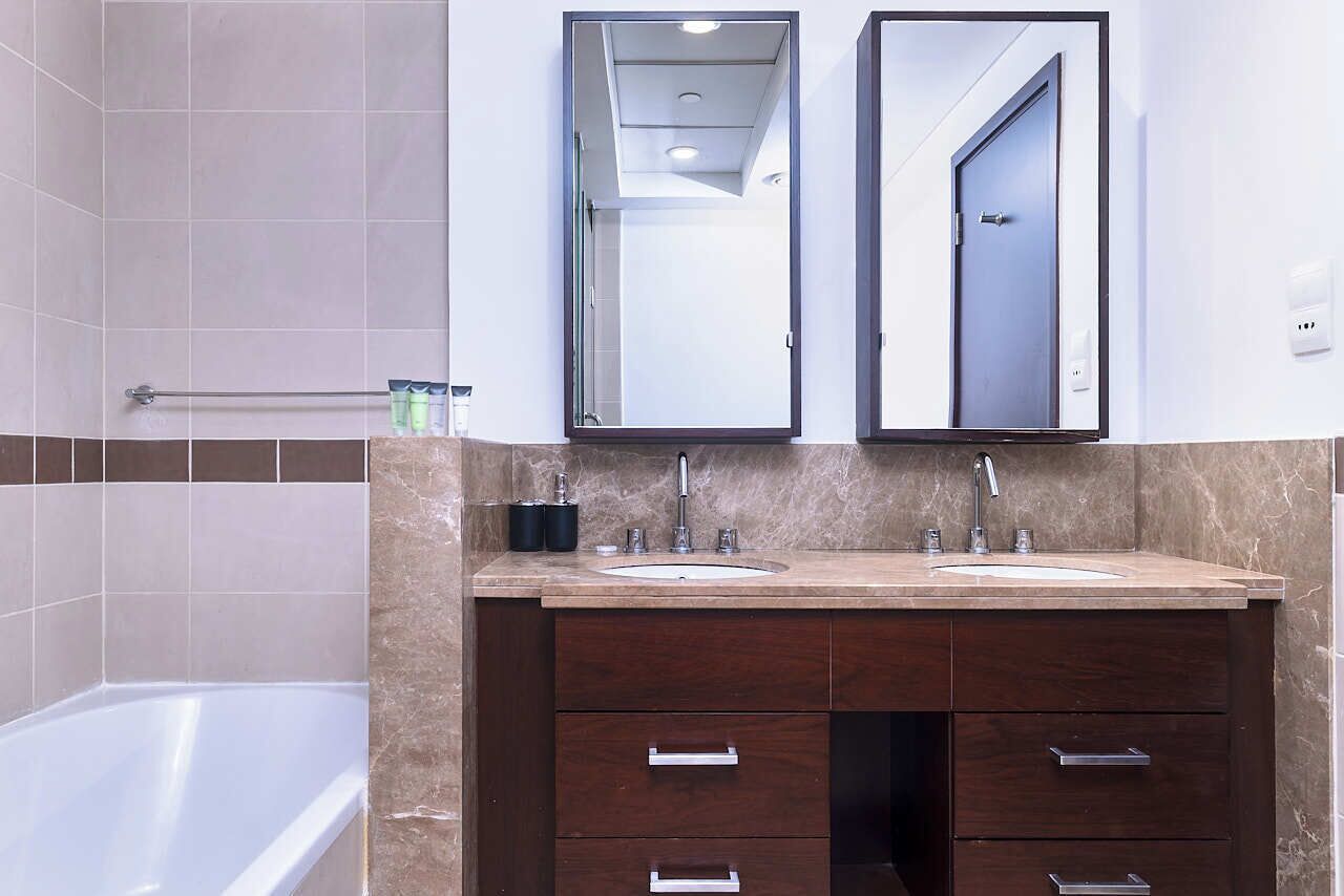 Ein modernes Badezimmer mit Badewanne, zwei Waschbecken und einem Waschtisch mit Schubladen.