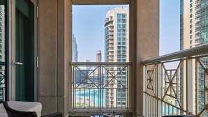 A balcony with wicker furniture, a glass table, and a view of high-rise buildings and a marina. - Bellavista-Striking-1Bedroom with Annex (Dubai)