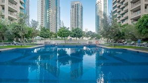 A swimming pool surrounded by high-rise buildings, trees, and sun loungers. - Bellavista-Striking-1Bedroom with Annex (Dubai)