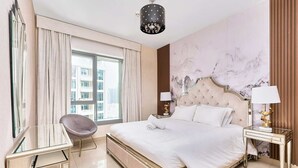 A spacious bedroom with a large bed, a desk, and a chair. - Bellavista-Striking-1Bedroom with Annex (Dubai)