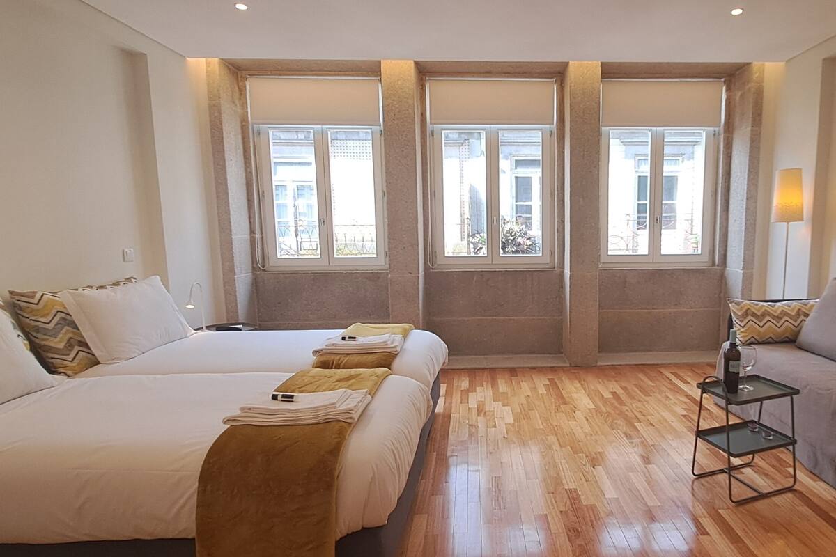 A hotel room with two beds, a sofa, a small table, and a TV.