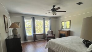 Un dormitorio con cama, escritorio, silla, cómoda y ventilador de techo.