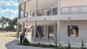 A modern building with a circular design, featuring a covered outdoor area with columns and a balcony. - Dikukama Executive Hotel (Tshabong)