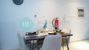 Un comedor con una mesa dispuesta para cuatro, un reloj en la pared y un extintor colgado en la pared.