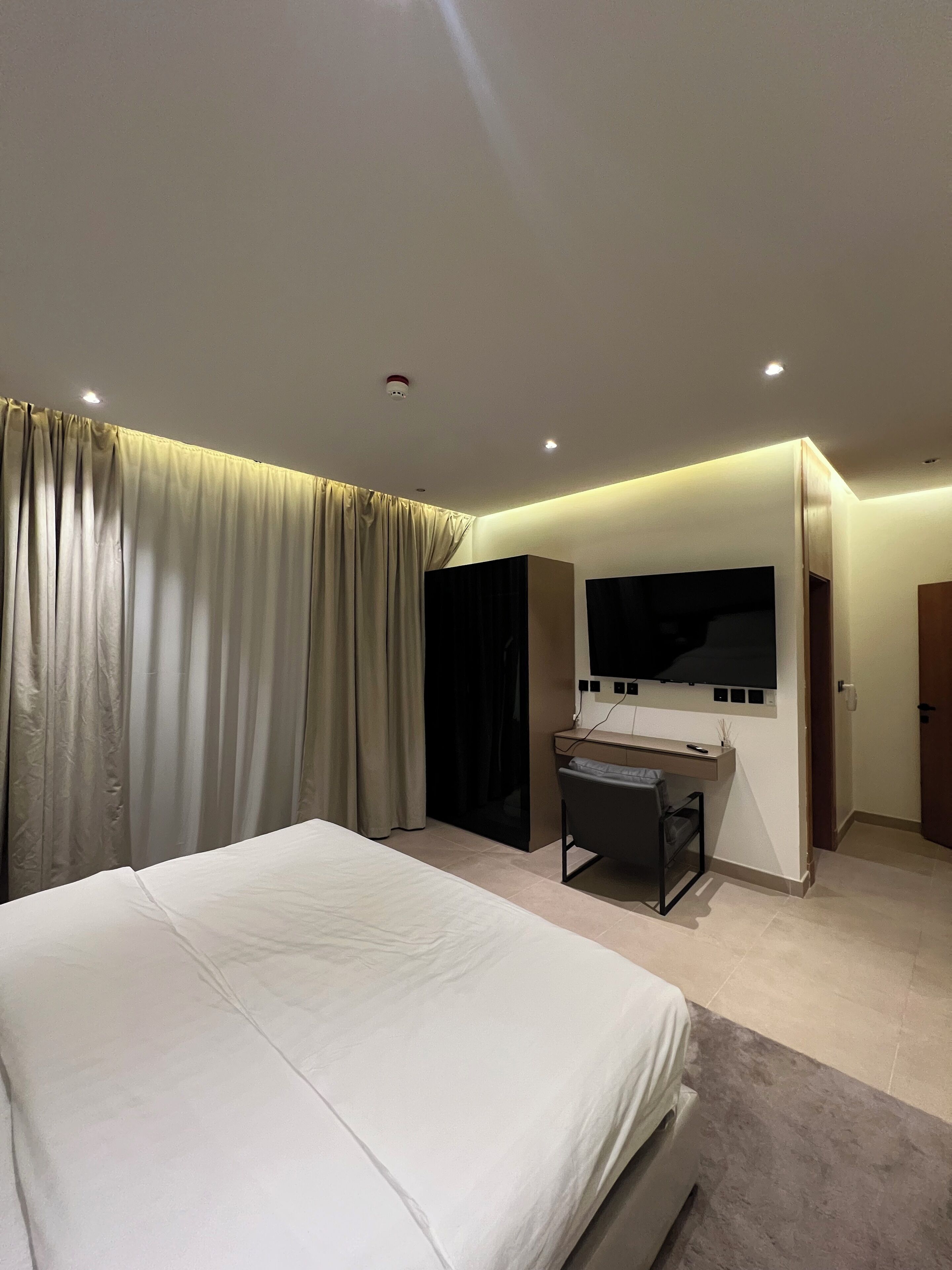 Une chambre d’hôtel moderne dotée d’un grand lit, d’un bureau et d’un téléviseur à écran plat fixé au mur.