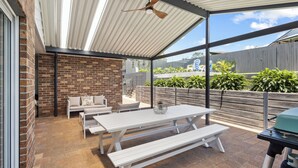 An outdoor patio with a brick wall, white furniture, and a grill. - SCOTTS RETREAT - RELAX BY THE POOL (Scotts Head)