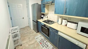 Una cocina compacta con armarios azules, cocina a gas, microondas y lavavajillas.