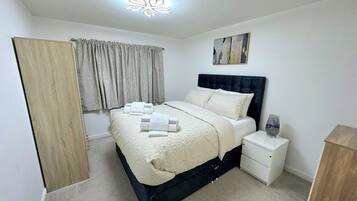 A neatly arranged bedroom with a bed, bedside table, and a nightstand.