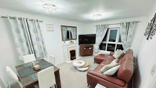 Una sala de estar con chimenea, un sofá, un televisor y un comedor.