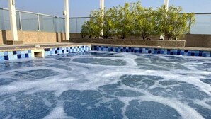 A hot tub with blue mosaic tiles, surrounded by a tiled deck and a glass enclosure. - Luxury Seaview Studio Apartment - RAK Al Marjan Island (Ras Al-Khaimah)
