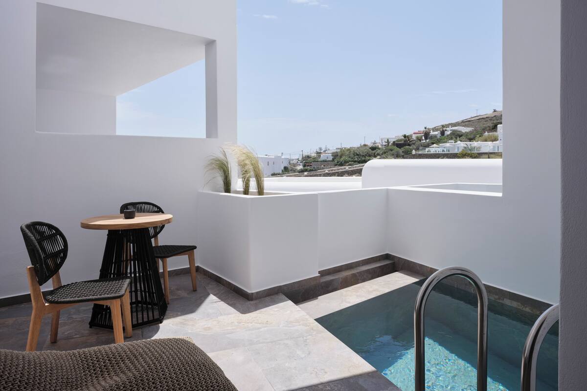 A modern balcony with a pool, a dining area, and a view of the coastline.