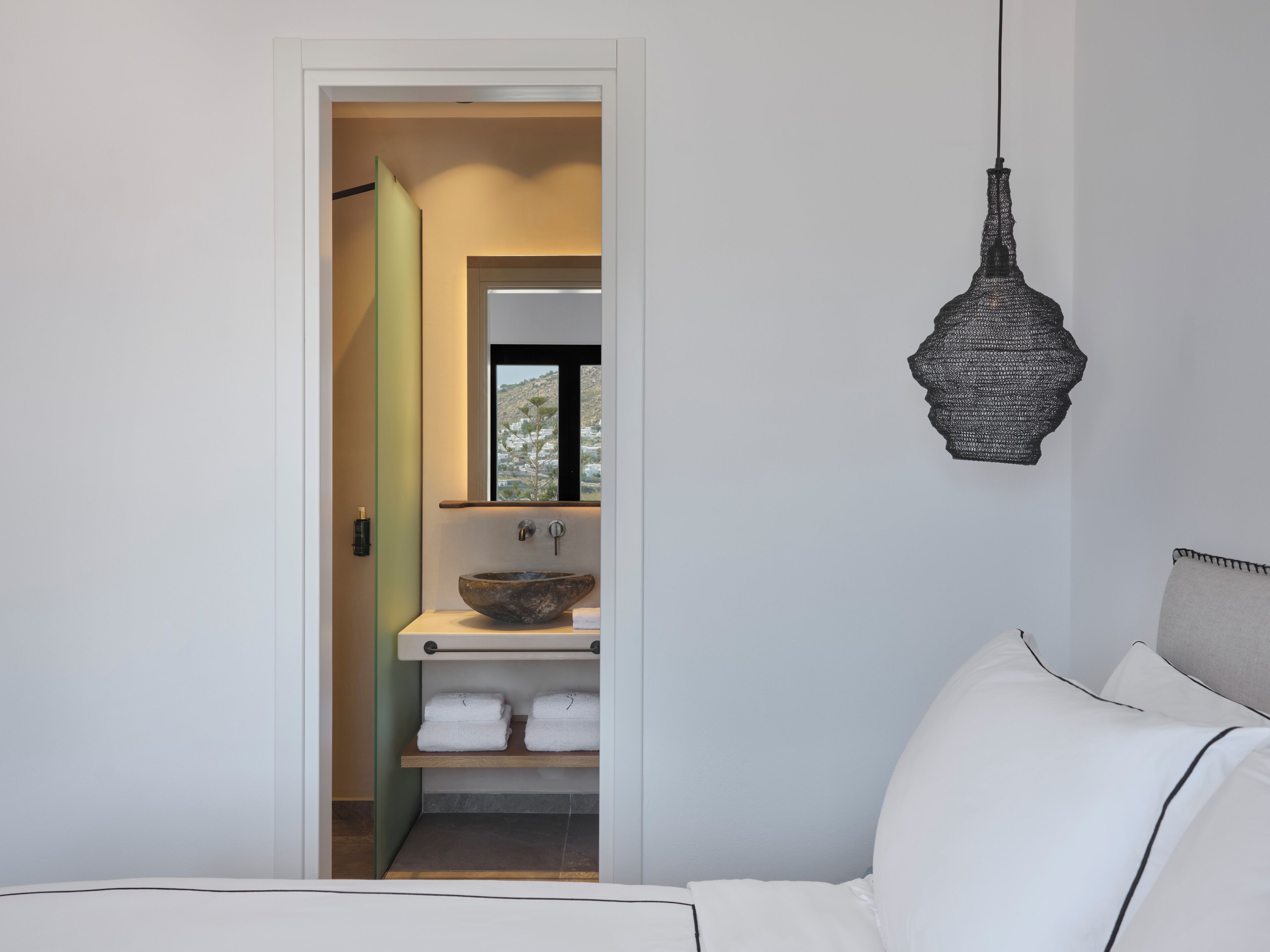 Een moderne badkamer met een grote spiegel, een wastafel op voet en een hangende lamp.