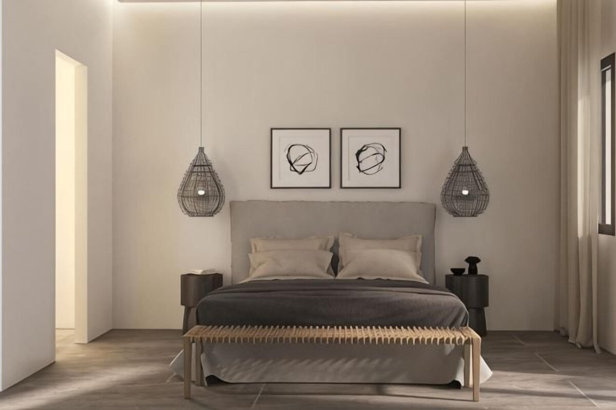 Un dormitorio moderno con cama, dos lámparas colgantes fijadas a la pared y dos obras de arte enmarcadas.