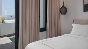 Ein Hotelzimmer mit einem Bett, beigen Vorhängen, einem Fenster und einer Pendelleuchte.