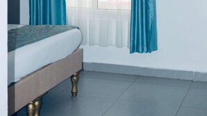 Un dormitorio con cama, ventana con cortinas y un equipo de aire acondicionado.