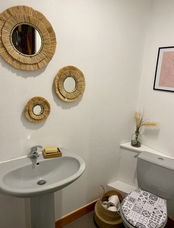Un baño con un lavamanos blanco, un inodoro y un espejo con tres adornos circulares en la pared.