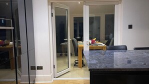 Une cuisine moderne avec un plan de travail foncé et une table à manger en bois, accompagnée de chaises.