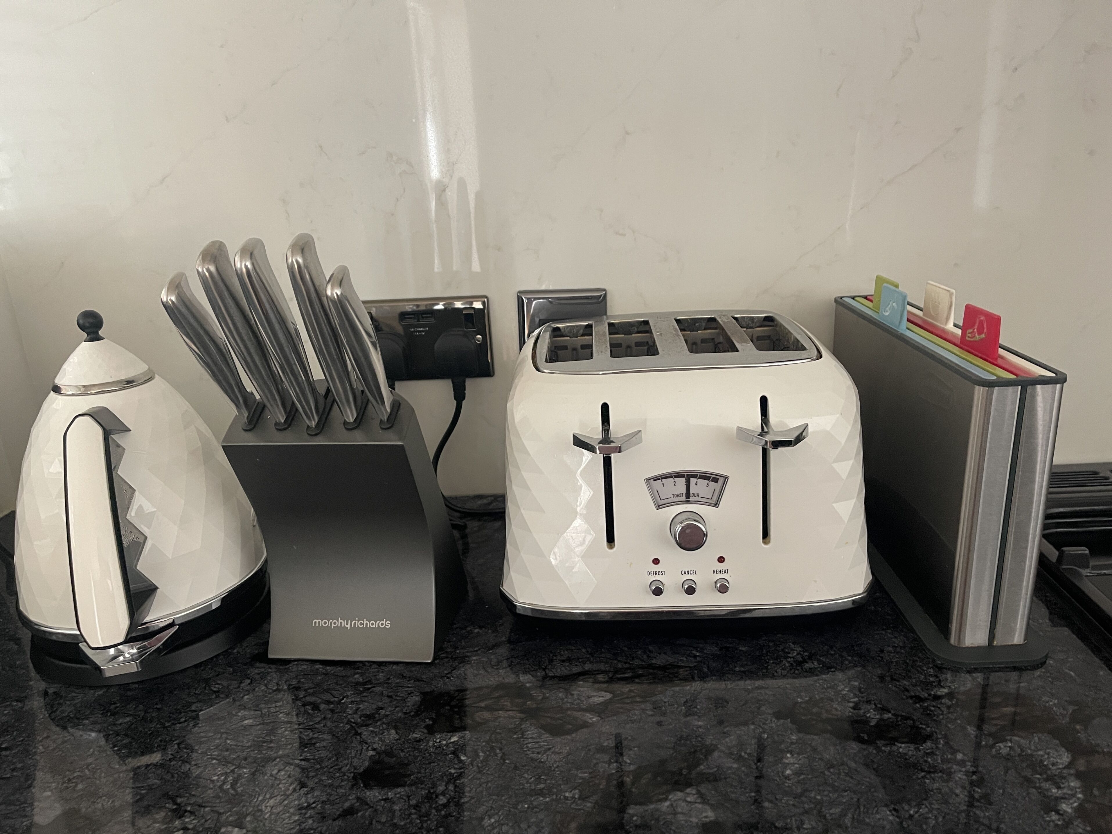 A kitchen with a toaster, a kettle, and a knife block.
