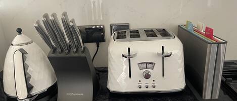 A kitchen with a toaster, a kettle, and a knife block.