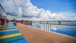 A swimming pool with a view of the water and clouds.