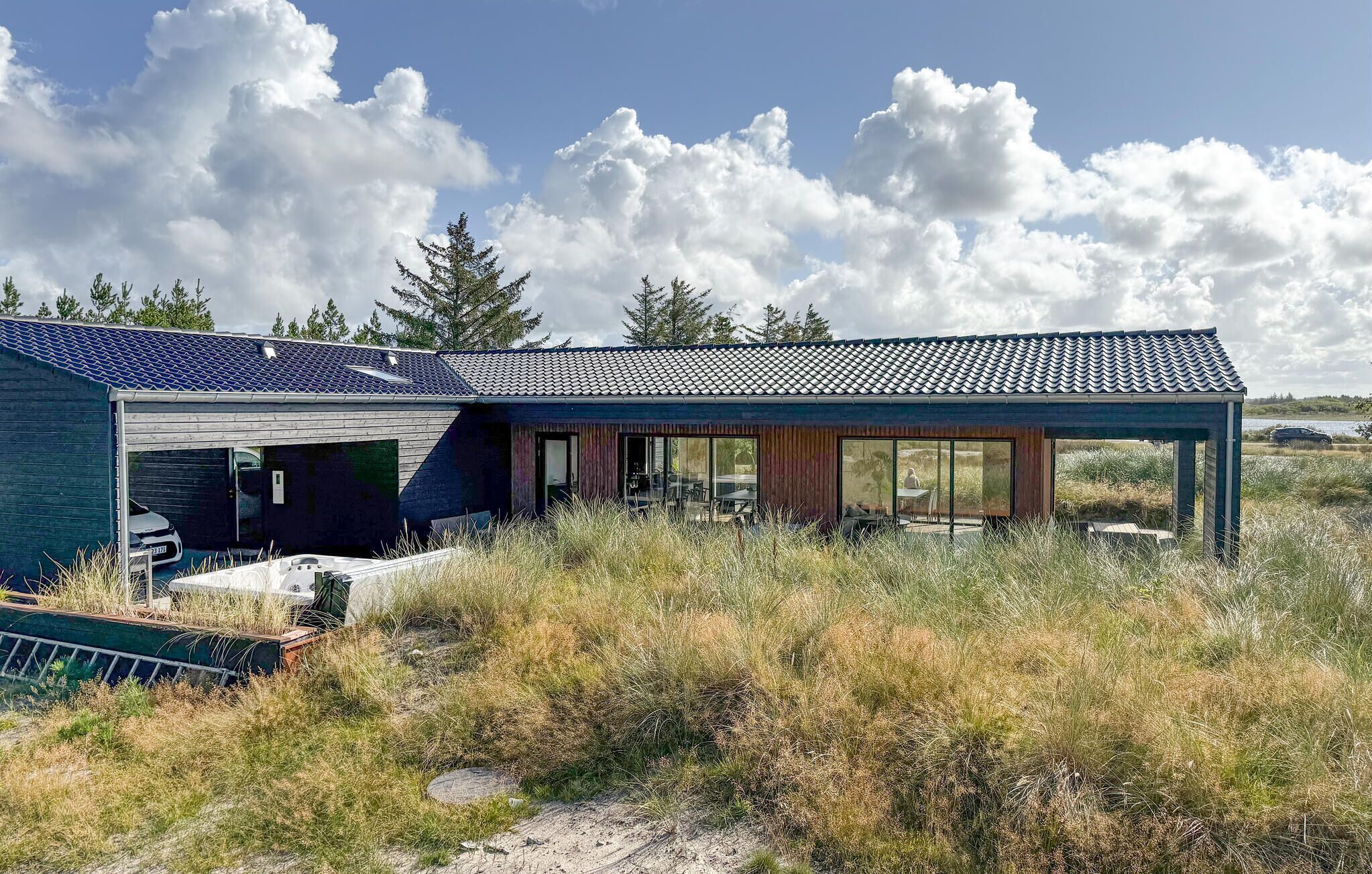 A modern house with a large glass facade, a covered patio, and a garage.