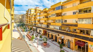 A multi-story yellow building with balconies, outdoor seating, and a central courtyard. - Inftour Apolo III Atico (Calp)