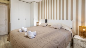 A hotel room with a large bed, a wardrobe, and a bedside table with a lamp. - Inftour Apolo III Atico (Calp)