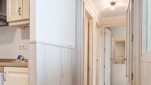 A hallway with a white air conditioning unit, a kitchen area with cabinets, and a marble floor. - Inftour Apolo III Atico (Calp)