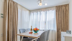 A dining area with a wooden table, grey chairs, a fruit bowl, wine glasses, and a bottle. - Inftour Apolo III Atico (Calp)