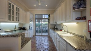 A kitchen with white cabinets, granite countertops, a built-in oven, a sink, and a view of the backyard through a sliding glass door. - 3Br Apt-quinta do Lago-private Terrace (Loulé)