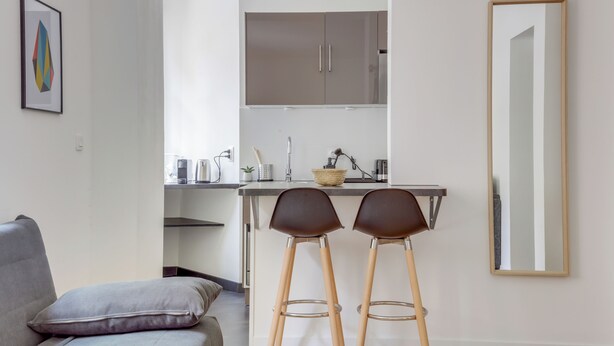 A modern kitchen with a bar area, two stools, and a large mirror. - Le Recollet - Versailles (Versailles)