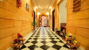 A hotel hallway with a checkered floor, wooden walls, and potted plants. - Hotel Mantra Heritage Jaisalmer (Jaisalmer)