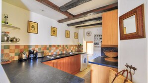 A kitchen with wooden cabinets, a black countertop, and a tiled backsplash. - House in the heart of Sarlat for 4 people (Sarlat-la-Canéda)