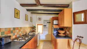 A kitchen with wooden cabinets, a black countertop, and a tiled backsplash. - House in the heart of Sarlat for 4 people (Sarlat-la-Canéda)
