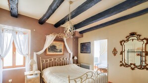 A bedroom with a four-poster bed, a nightstand, a bedside table, a chandelier, a large mirror, and a window with curtains. - House in the heart of Sarlat for 4 people (Sarlat-la-Canéda)