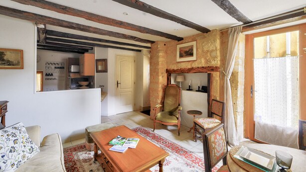 A traditional living room with exposed wooden beams, a fireplace, a dining table, and a sofa. - House in the heart of Sarlat for 4 people (Sarlat-la-Canéda)