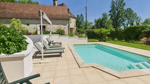 Ein Poolbereich mit Liegestühlen und einem Haus im Hintergrund.