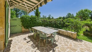 Eine Außenpatio mit Steinboden, einem Tisch und Stühlen sowie einem grünen Tor.