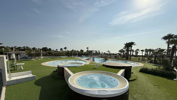 A pool area with three hot tubs, a slide, and a small table.